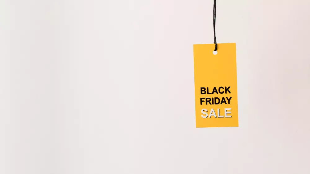 Etiqueta amarilla colgante con el texto "Black Friday Sale" en negro y blanco, destacando una promoción especial. La etiqueta cuelga de un cordón negro sobre un fondo claro, simbolizando la simplicidad y efectividad en el diseño de etiquetas de producto para campañas de ventas.