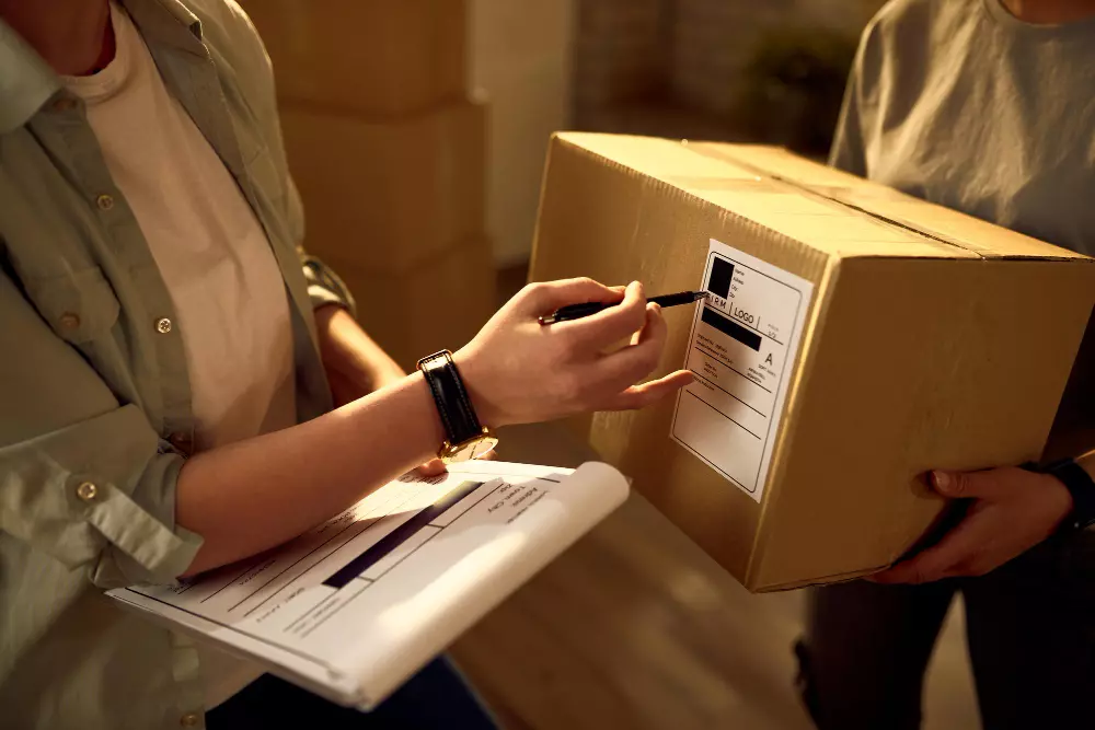 Persona revisando una caja de envío mientras realiza un pedido de impresión personalizado, asegurándose de que todos los detalles del pedido estén correctos antes de la entrega.