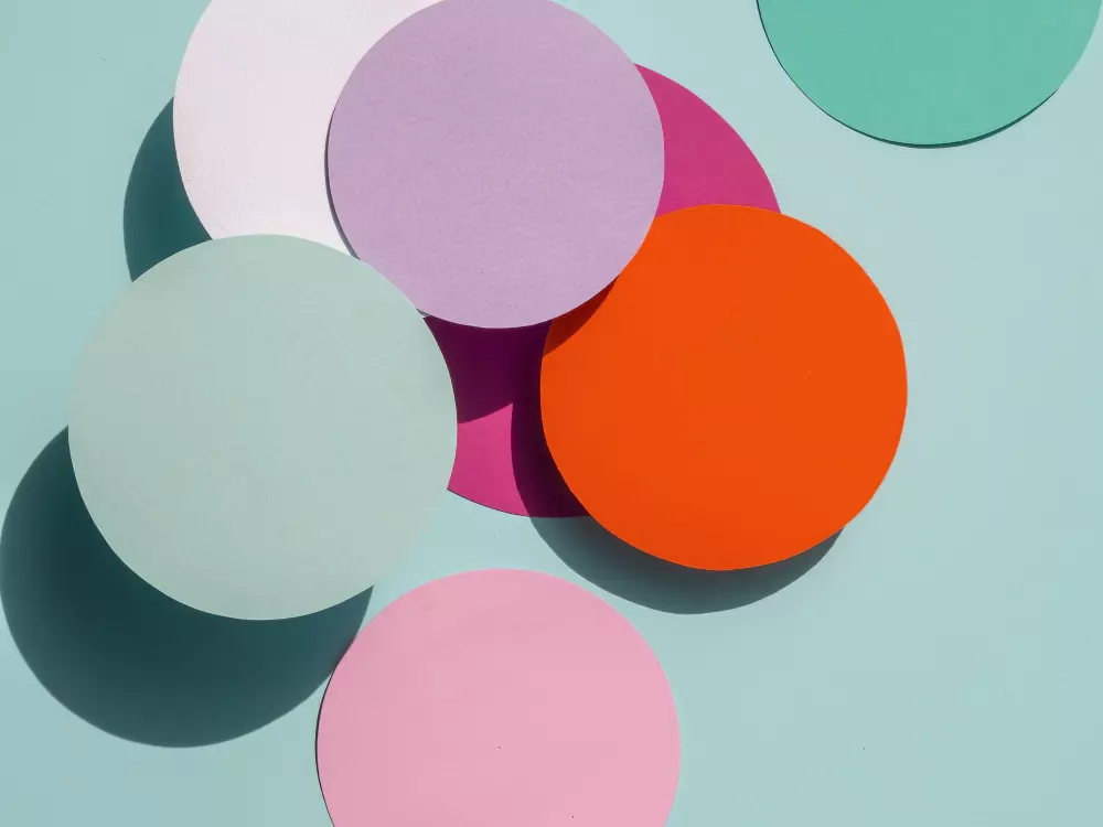 Círculos de papel de colores brillantes que representan opciones creativas y asequibles para la impresión de flyers troquelados baratos, ideales para destacar la identidad de una marca.