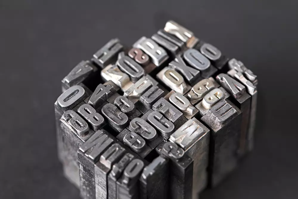 Bloques de metal con diferentes letras utilizados en impresión tipográfica tradicional, representando la importancia de elegir la tipografía adecuada para impresos para lograr una lectura clara y efectiva.
