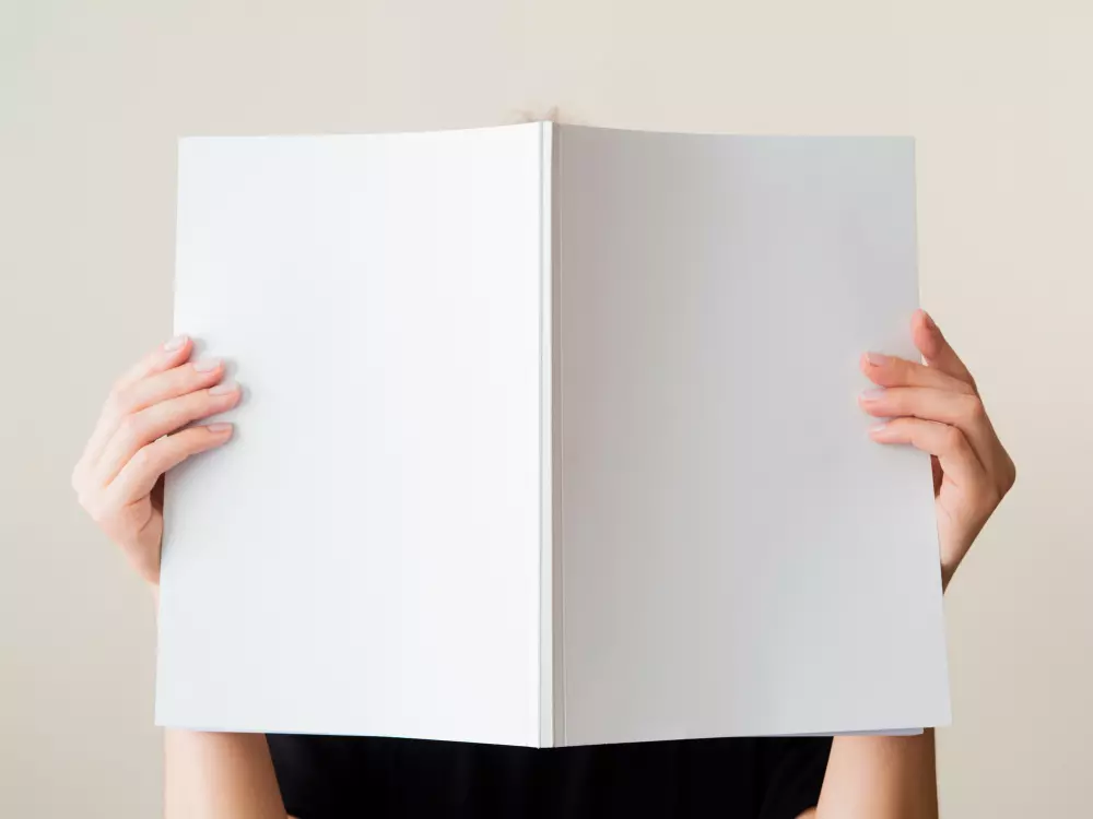 Persona sosteniendo un catálogo en blanco, lista para diseñar su propio material corporativo. Sigue estos consejos para diseñar catálogos empresariales y crea un catálogo atractivo y funcional para tu negocio.